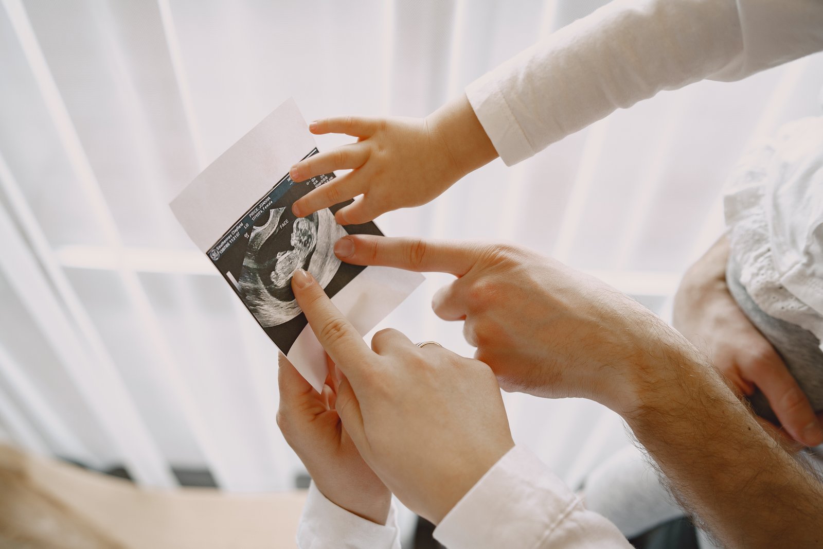 Best Pregnancy Screening Services in Phoenix, AZ (2026 Guide) 1 mom dad daughter watching ultrasound picture baby family light clothes family expecting baby